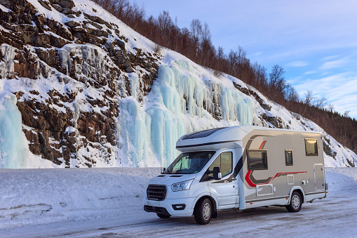 The camper under beautiful blue ice wall in winter Norway