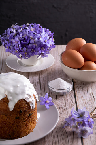 In this vertical photo, a homemade Easter cake, also known as kulich, takes center stage, embodying Christian tradition and celebration. The image captures the essence of religious festivities, with a symbolic egg and a rich connection to time-honored customs. symbol, table, icing, glazed, catholic