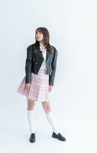 Asian school girl with brown hair wearing a black leather jacket and pink plaid skirt