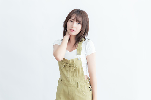 A young woman in a white shirt and khaki overalls