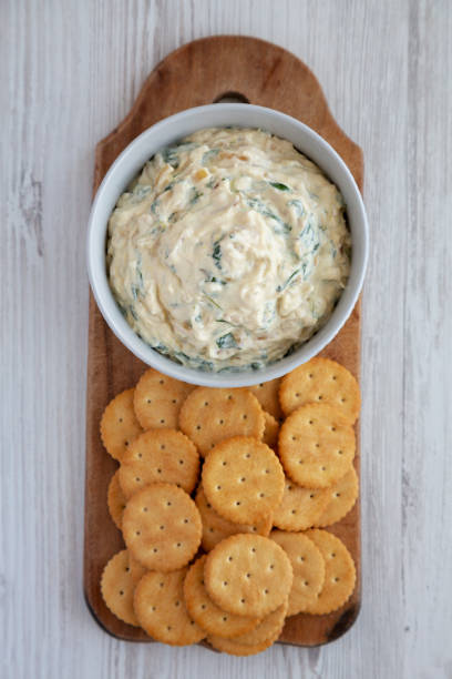 istock Homemade Caramelized Onion and Spinach Dip with Salty Round Crackers, top view. Flat lay, overhead, from above. 1910046378