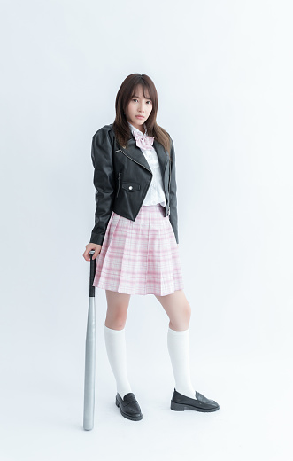Asian school girl in a pleated skirt holding a baseball bat