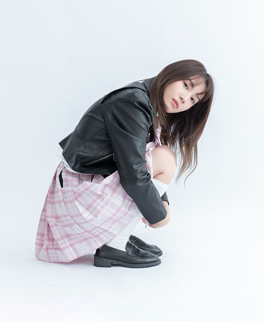 Asian school girl in pleated skirt and leather jacket