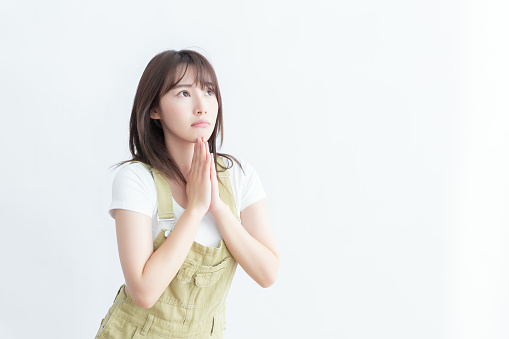 Young woman in casual clothes praying with a hopeful expression