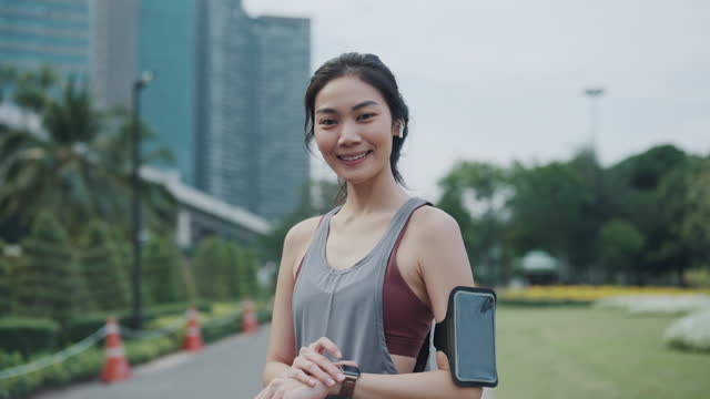 Active Woman Syncs Fitness App with Smartphone Tech in Urban Park.