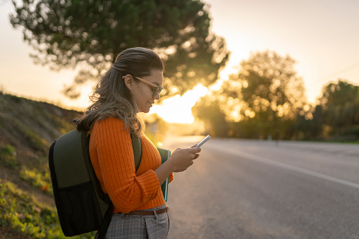 Mature woman using smartphone on road in natural landscape