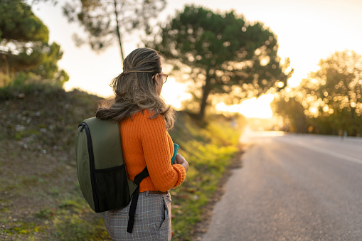 Mature backpacker woman looking at natural scenery on the road