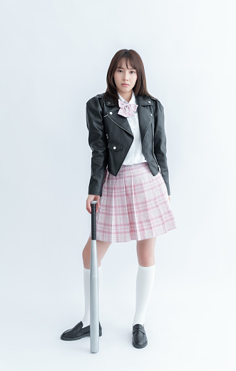 Asian school girl in plaid skirt holding a baseball bat