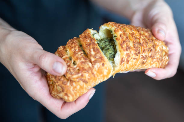 istock A hand breaks a spinach bun in half close-up. Eating quick snacks. 1910133736