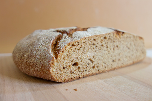 Homemade artisanal sliced sourdough bread on a napkin and butter with knife. Healthy home baking concept.