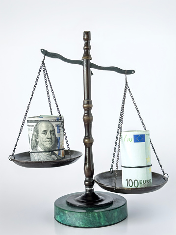Still life of a scale of justice with roll of Dollar and Euro bills