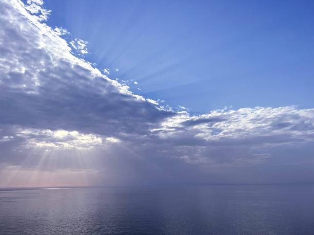 istock Sun rays through sky clouds shine on the sea. 1910203315
