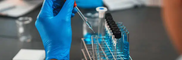 Scientist conduct chemical experiment in medical laboratory, carefully drop precise amount of liquid from pipette into test tube for vaccine drug or antibiotic development. Neoteric