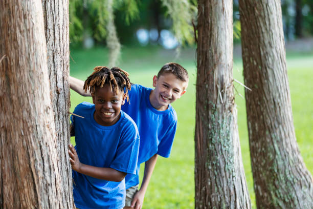 istock Two boys playing at park, peeking out from behind trees 1910259952