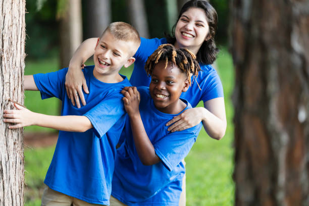 istock Two boys with camp counselor in park at summer camp 1910259983