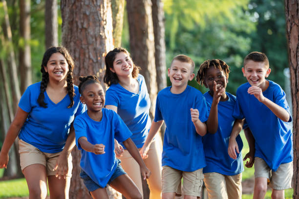 istock Multiracial children, counselor at summer camp, running 1910260407