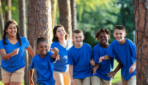 istock Multiracial children, counselor at summer camp, running 1910260492