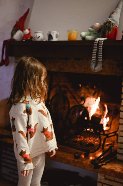 istock Cute little girl looking at fireplace at home. 1910271783