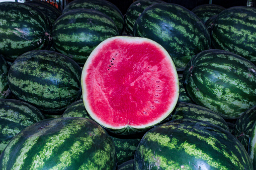 Half of a watermelon, Citrullus lanatus, with a portion of fresh watermelons