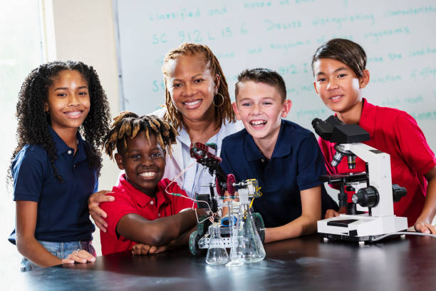 Caucasian smart teacher support excited curious student pour colored liquid in beaker at laboratory. Creative children concentrate to do experiment and enjoy inspecting biochemical sample. Pedagogy.