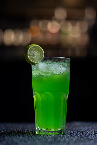 A chilled green beverage with a slice of lime garnish served in a tall glass