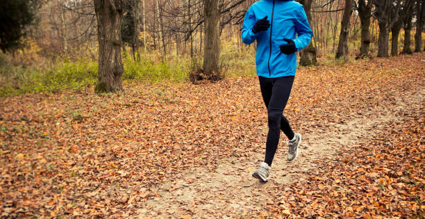 istock The young  man is running through the autumn park by pathway 1910307422