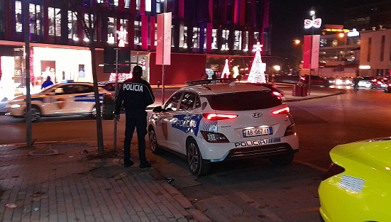 Tirana, Albania - December 20, 2023: Albanian Police Officer Standing, Albanian Police Land Vehicle, Air Albania Stadium Building Exterior, Road Traffic, Retail Store, People, Christmas Tree, Christmas Decorations, Taxi Vehicle And More Scene In Downtown Tirana, Balkan Peninsula, Southeastern Europe
