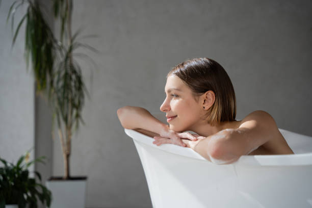 istock Relaxed woman leaning on bath edge and smiling in spa. 1910388861