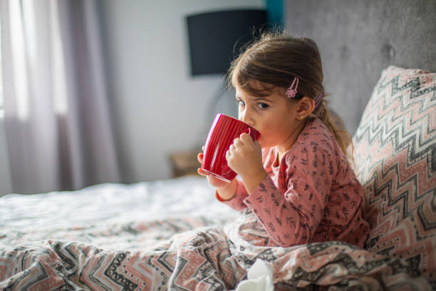 istock Sick girl drinking tea in bed 1910407053