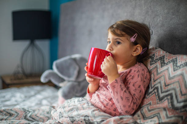 istock Sick girl drinking tea in bed 1910407065