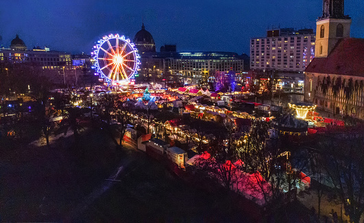 Amazing drone point of view on Christmas market next to St. Mary's Church and Berlin Fernsehturm in blue hour in evening Berlin with Christmas lights of marlet stalls
. Ice rink in centre of market.