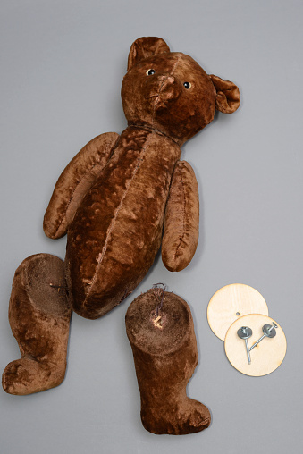 broken toy teddy beer with severed paws on a neutral background