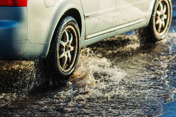 car wheel in puddle. torrential rain. - skidding car tire rain stock-fotos und bilder