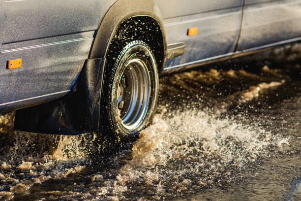 car wheel in puddle. torrential rain. - skidding car tire rain stock-fotos und bilder