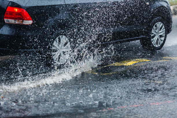 car wheel in puddle. torrential rain. - skidding car tire rain stock-fotos und bilder