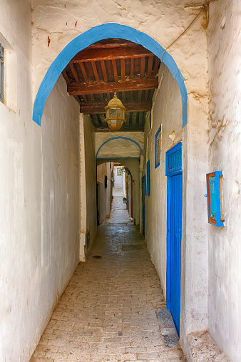 Narrow passage street with blue door of houses in the kasbah of Tangier, Morocco