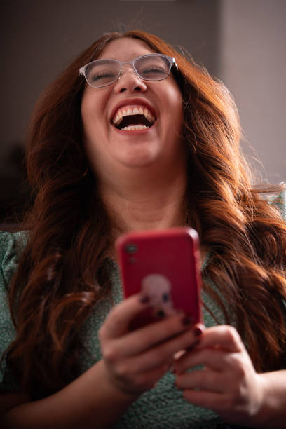istock red head woman looking at her cellphone laughing 1910527604