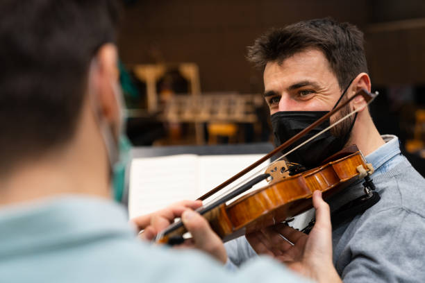 istock Man playing violin with the help of his teacher 1910592524