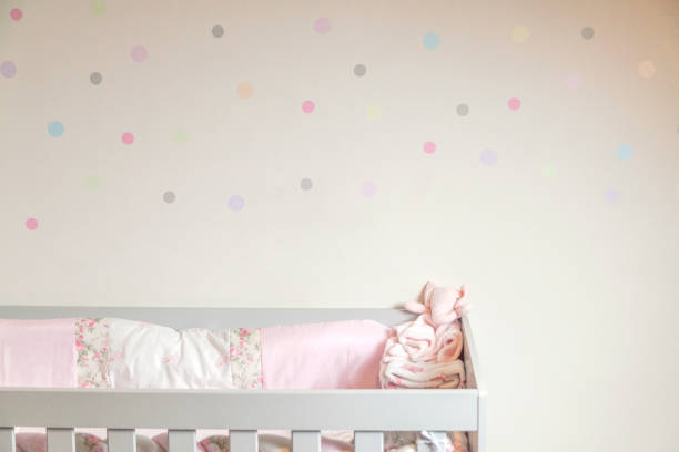 istock Baby crib with colorful polka dot wal 1910613689