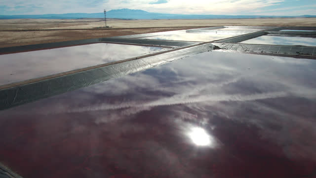 Drone Shot of a Oilfield Water Retention Ponds in Eastern Utah Near Thompson Springs on a Sunny Winter Day with The Dramatic Sky Reflecting in the Water