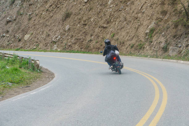 motocykl pokonujący zakręt na górskiej drodze. kierowca nosi kask - lane sunlight sunbeam plant zdjęcia i obrazy z banku zdjęć
