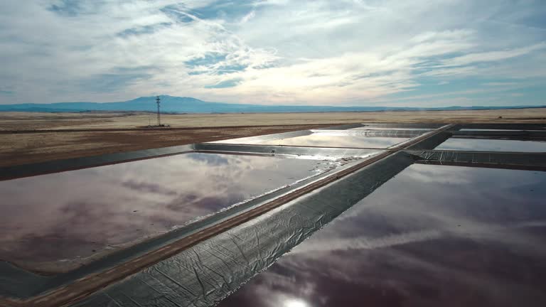 Drone Shot of a Oilfield Water Retention Ponds in Eastern Utah Near Thompson Springs on a Sunny Winter Day with The Dramatic Sky Reflecting in the Water