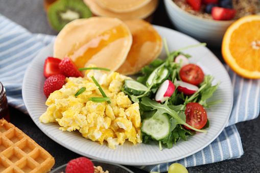 fresh scrambled eggs on white plate on breakfast table