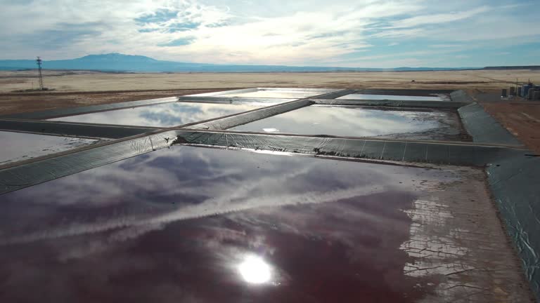 Drone Shot of a Oilfield Water Retention Ponds in Eastern Utah Near Thompson Springs on a Sunny Winter Day with The Dramatic Sky Reflecting in the Water