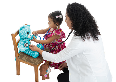 Mother and daughter playing doctor with stuffed teddy bear.