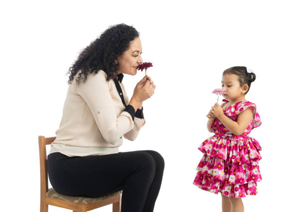 Mother and daughter each smelling a flower.