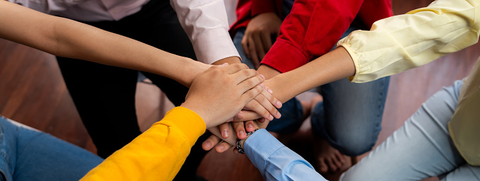 Closeup shot of a diverse group of people holding hands together in unity