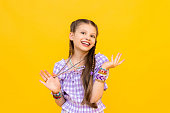 The child put on a lot of bracelets made of beads and beads. A happy little girl is enjoying a beaded ornament. Beading for children. Isolated yellow background.