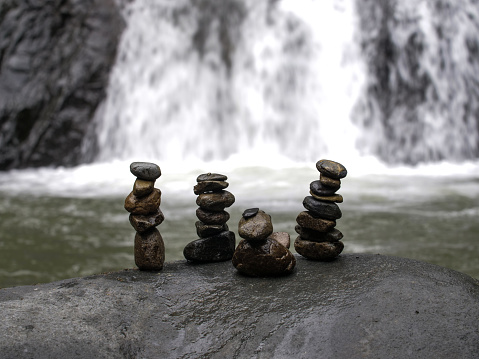 a pile of small stones on top of a large stone with a waterfall in the background