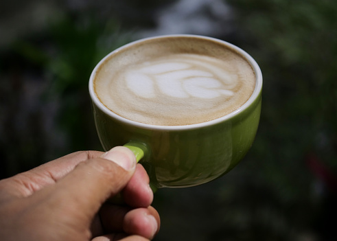 Female hand with cup of coffee on river background